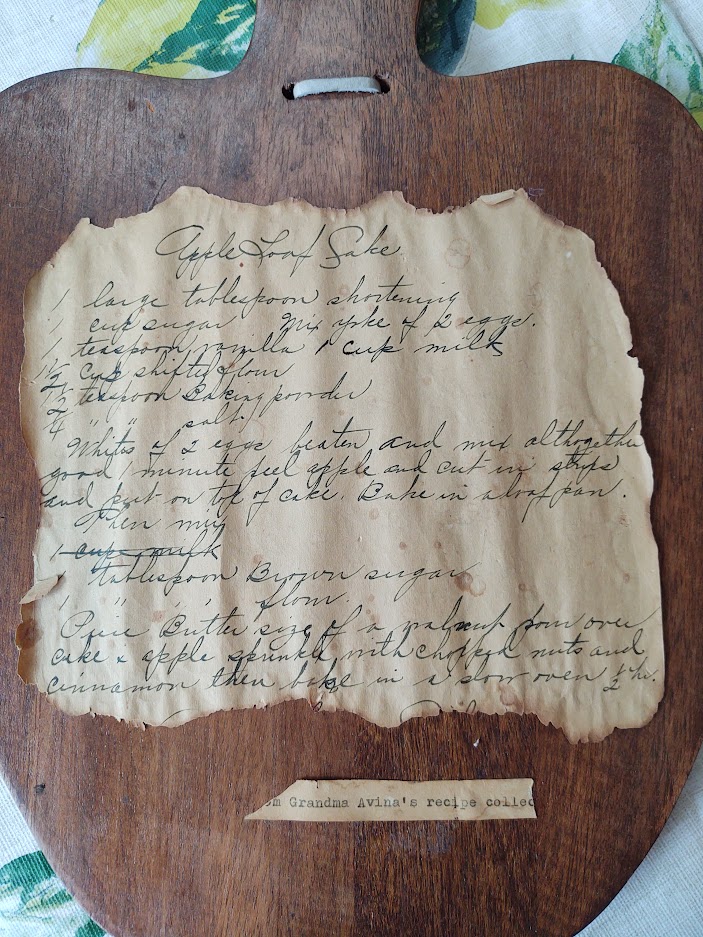 Photo shows a handwritten recipe for Apple Loaf Cake mounted on a piece of polished wood. From the early 1900s.